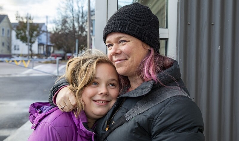 Adult and child outside CVOEO office embrace and smile.