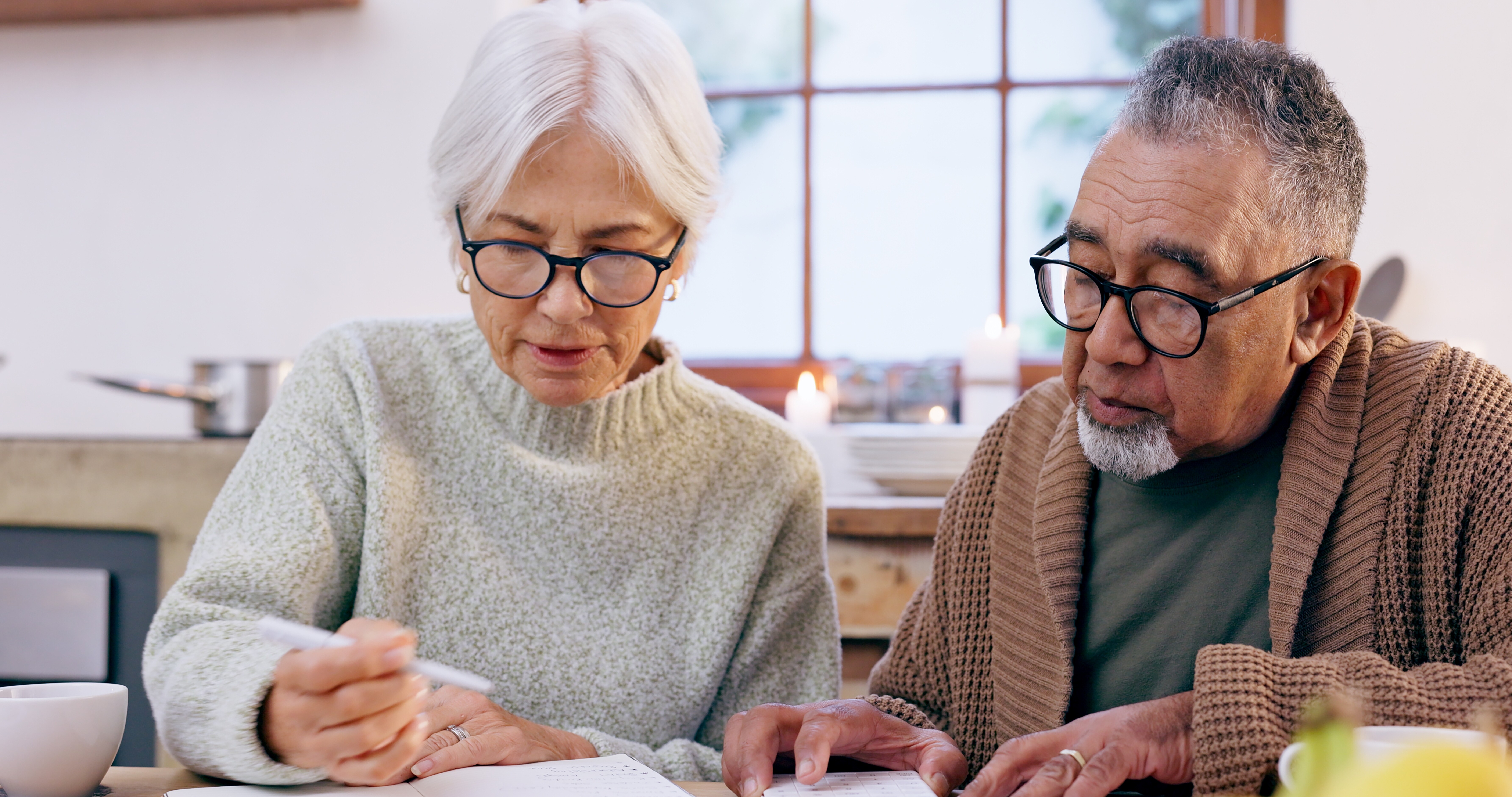 Photograph of a couple reviewing their charitable gifts they plan to leave in the will to CVOEO a Vermont based nonprofit. Both people are wearing glasses and looking down at estate planning documents on a wooden table.&nbsp;