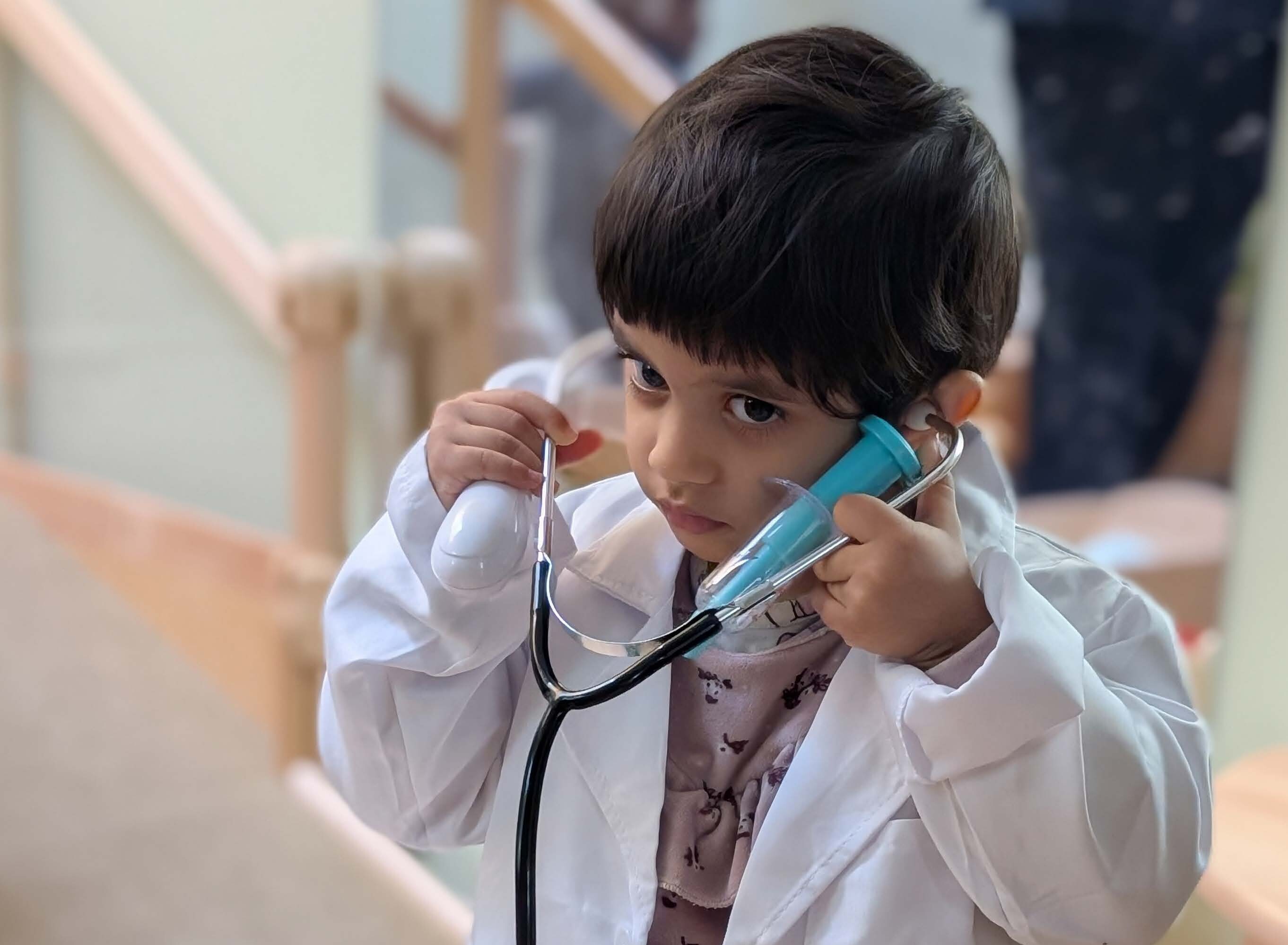 Image of Halla, a child wearing a doctor's lab coat and wearing a stethoscope&nbsp;