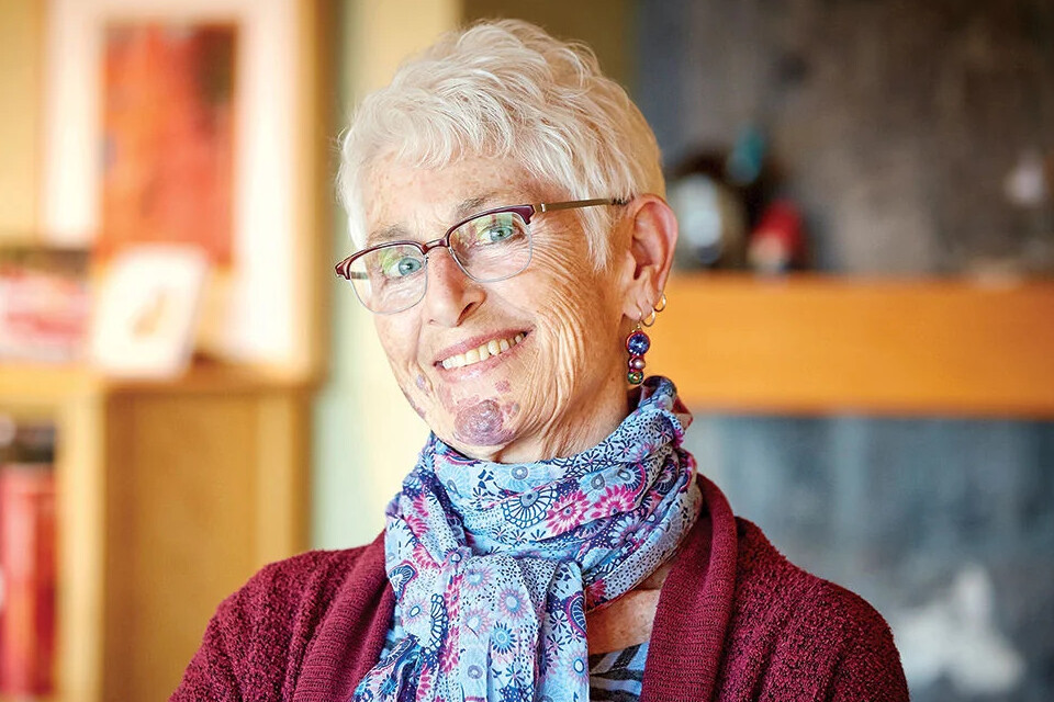 Headshot of Patricia Fontaine smiling towards the camera wearing a red sweater and a floral scarf.