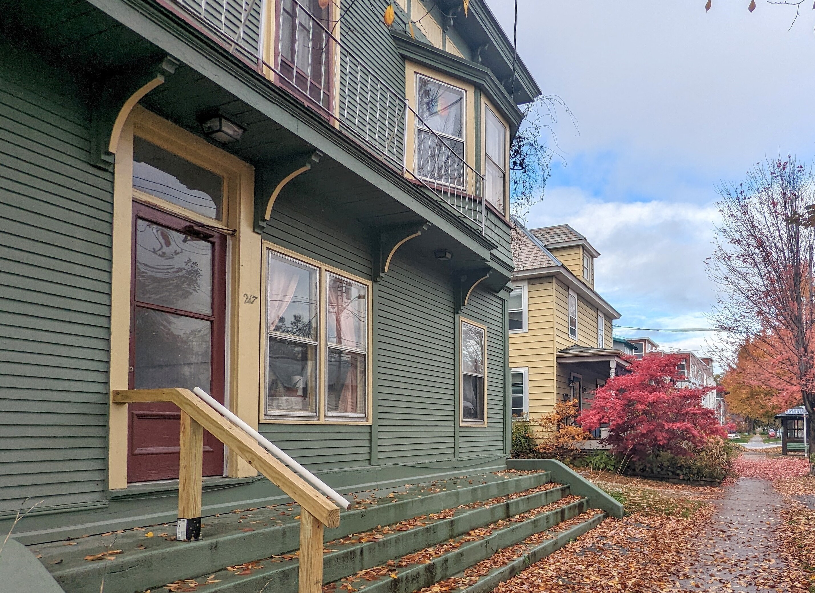 Teal apartment with front steps and sidewalk in Fall